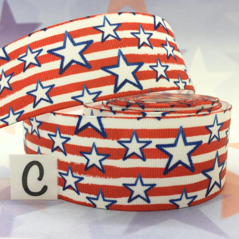 May include: Red, white, and blue ribbon with a stars and stripes pattern. The ribbon is rolled up and the letter "C" is visible on the left side of the image.