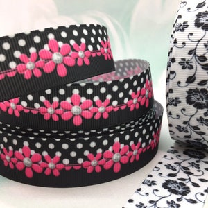 May include: Three rolls of black and white ribbon with a polka dot pattern and pink flowers. The ribbon is 1 inch wide.
