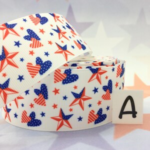 May include: White ribbon with a red, white, and blue pattern of stars and hearts. The ribbon is rolled up and the letter "A" is visible on a white square.