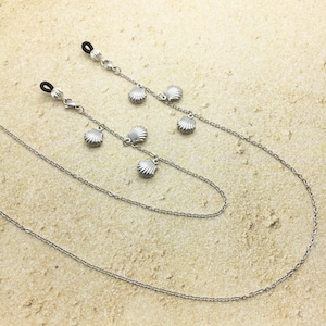 May include: Two silver chains with small seashell charms, designed to hold glasses.