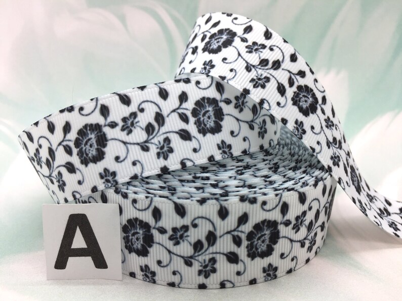 May include: White satin ribbon with a black floral print. The ribbon is rolled up and the label "A" is visible.