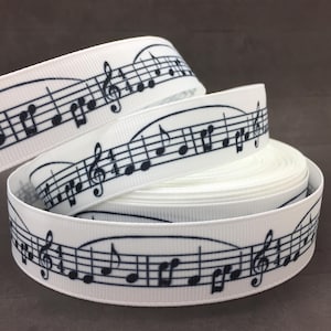 May include: White satin ribbon with a black musical note design. The ribbon is rolled up and shows the design repeating.