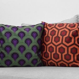 May include: Two decorative throw pillows with geometric patterns. One pillow has a green and purple pattern, the other has a red and orange pattern.