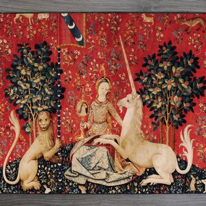 May include: A tapestry depicting a unicorn being led to a woman by a lion. The woman is seated on a throne and holding a mirror. The tapestry is set against a red background with a variety of flowers and plants.