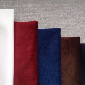 May include: Five fabric swatches, one white and four different shades of velvet: burgundy, navy blue, brown, and black.