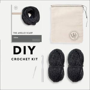 May include: DIY crochet kit for making a scarf. The kit includes two balls of dark gray yarn, a crochet hook, a tapestry needle, and a pattern for the "The Anello Scarf".