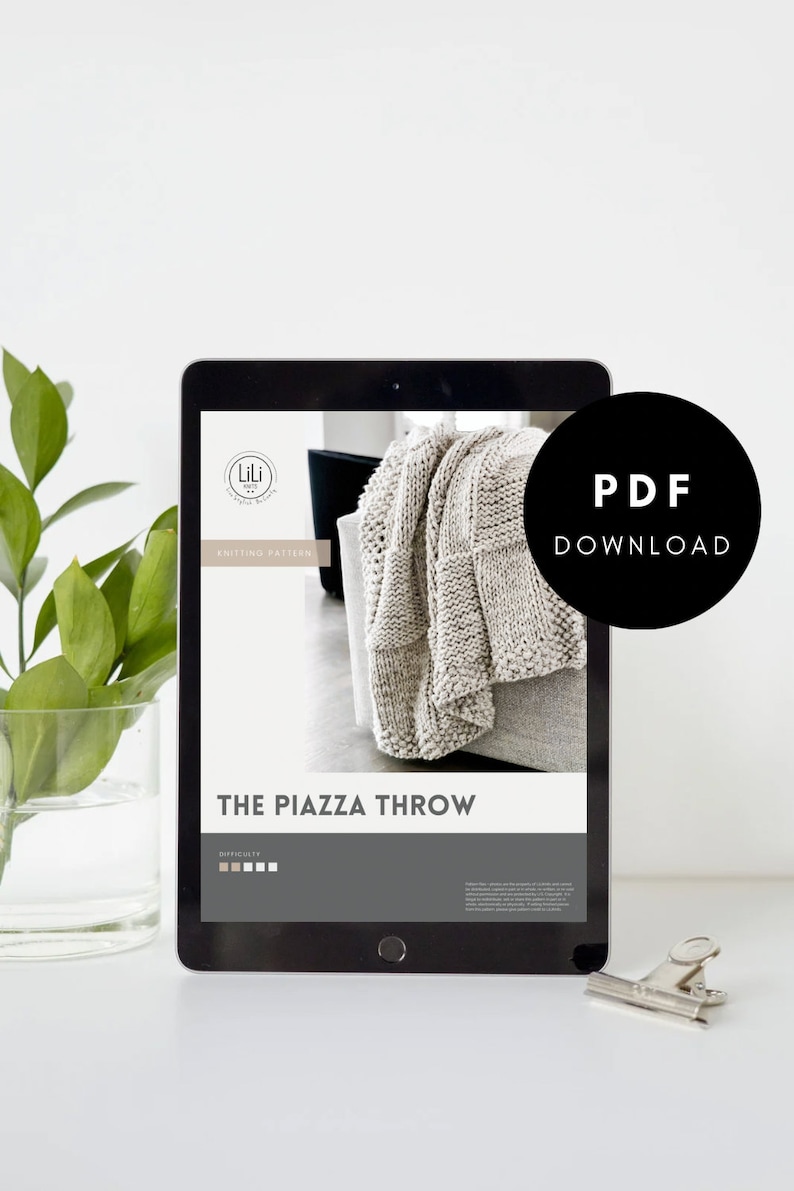 May include: A digital tablet displaying a knitting pattern for a throw blanket called "The Piazza Throw". The pattern is from Lili Knit Designs and includes a difficulty rating. The text "PDF Download" is displayed in a black circle on the screen.