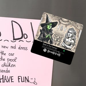 May include: A black and white illustration of a witch and a princess from the musical Wicked. The witch is wearing a green dress and a pointed hat. The princess is wearing a white dress and a crown. The text "What Is This Feeling?" is written at the bottom of the image.