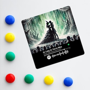 May include: A black and green digital illustration of a scene from the musical Wicked. The image features Elphaba and Glinda standing on a stage with a crowd of people in the background. The text "As Long As You're Mine" is displayed on the image, along with a Spotify logo and a Spotify code.
