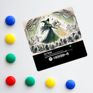 May include: A black and white illustration of two women singing on stage. The woman on the left is wearing a green dress and a witch's hat. The woman on the right is wearing a yellow dress. The text "For Good" is displayed on the image. The image is a Spotify music player screen.