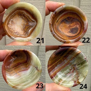 以下が含まれることがあります： 緑、茶色、クリーム色の4つの丸い磨かれたオニキスボウル。各ボウルには、渦巻く色とテクスチャのユニークなパターンがあります。ボウルには21、22、23、24の数字が見えます。これらのボウルは、小さなアイテムを入れるのに最適です。