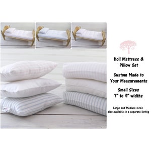 May include: A set of three doll pillows in white with pink and blue stripes. The pillows are stacked on top of each other. The pillows are 7 to 9 inches wide and are custom made to your measurements. Doll Mattress & Pillow Set.