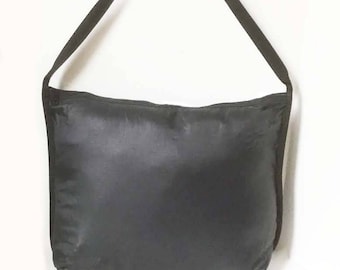 May include: A black shoulder bag made of a smooth, water-resistant fabric. The bag has a simple design with a single strap and a zipper closure.