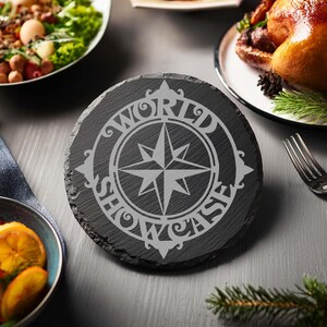 May include: A black slate coaster with a compass design and the words "World Showcase" engraved in white.