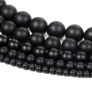 May include: A strand of black onyx beads in various sizes. The beads are round and smooth, and they are arranged in a graduated pattern, with the largest beads at the top and the smallest beads at the bottom.