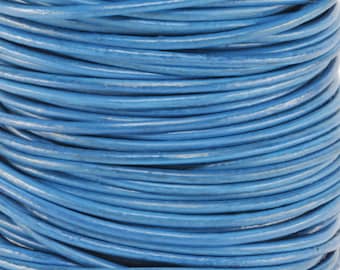 Op de afbeelding: Een spoel met blauwe lederen koord. Het koord is strak om de spoel gewikkeld en klaar om te gebruiken voor knutselprojecten.