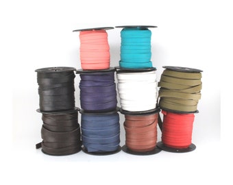 May include: Spools of leather cord in various colors, including black, brown, red, blue, white, green, and pink. The spools are stacked on top of each other.