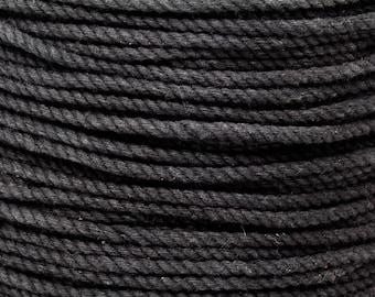 May include: Close-up of a tightly coiled, thick black rope. The rope is made of twisted fibers, creating a textured surface. The dark color and close perspective highlight the rope's construction and potential uses.