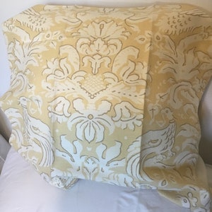 May include: A yellow fabric with a white damask pattern featuring stylized birds and floral designs.
