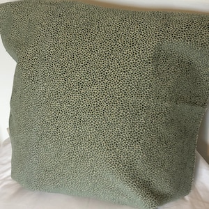 Puede incluir: Una almohada verde con un pequeño patrón moteado.