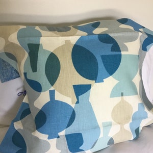 May include: A blue and beige patterned cushion with a geometric design. The cushion is made of a soft, linen fabric.