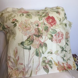 May include: A cream-colored pillowcase with a floral pattern featuring pink, red, and green flowers. The flowers are arranged in a vertical pattern on the fabric.