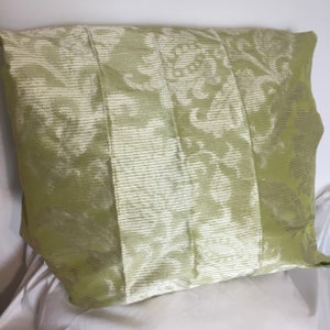 Pode incluir: Uma almofada verde com um padrão floral branco. A almofada é feita de um tecido macio e texturizado.