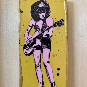 Könnte beinhalten: Eine Illustration einer Person, die Gitarre spielt, in Pink und Schwarz, auf gelbem Hintergrund mit schwarzen und goldenen Farbspritzern.