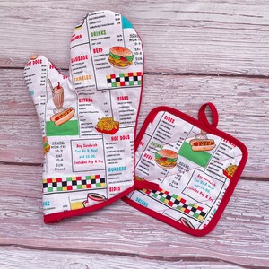May include: Two red and white oven mitts with a retro diner theme. The mitts feature a menu with food items like hot dogs, burgers, and fries. The text on the mitts reads "Hours: Mon-Fri 10-9 Sat 10-8 Sun Closed" and "Any Sandwich Can Be A Meal add $2.00 Includes Pop & Fry".