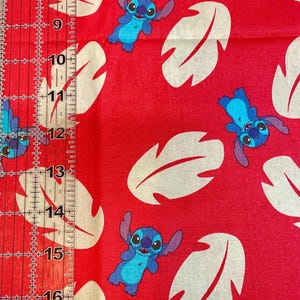 May include: Red fabric with a repeating pattern of the character Stitch in blue and white leaf shapes. Ideal for crafting projects, including quilting, clothing, and home decor.