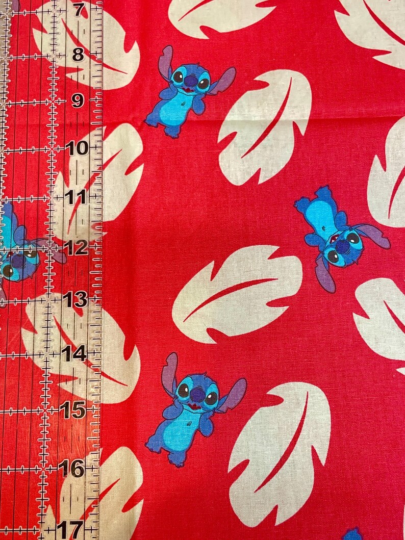 May include: Red fabric with a repeating pattern of the character Stitch in blue and white leaf shapes. Ideal for crafting projects, including quilting, clothing, and home decor.
