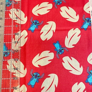 May include: Red fabric with a repeating pattern of blue and white Stitch characters and large cream-colored leaf shapes. A ruler with inch measurements is visible along the left side of the fabric.