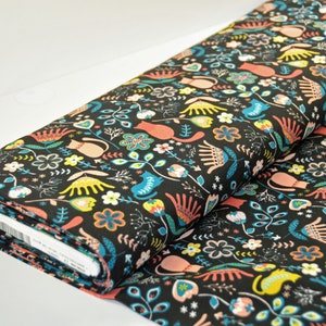 May include: Black fabric with a repeating pattern of colorful cats, flowers, and leaves. The fabric is rolled up and the label is visible.