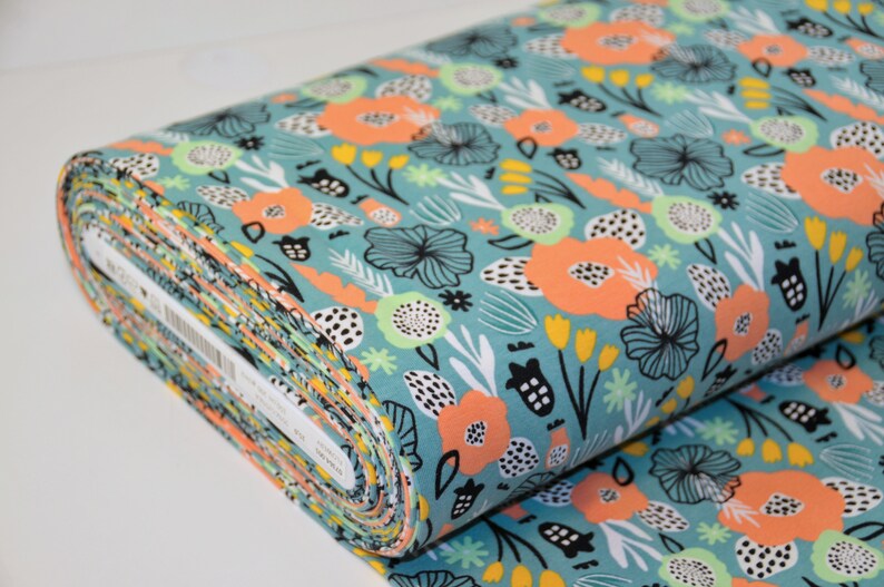 Puede incluir: Un rollo de tela turquesa con fondo blanco y un estampado floral colorido. El estampado presenta flores y hojas de color naranja, amarillo, verde y negro.