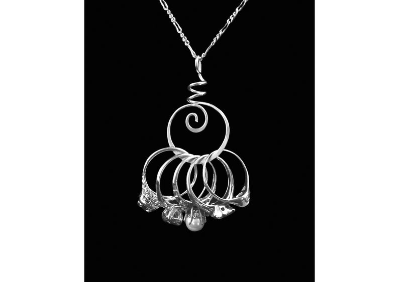 May include: A silver necklace with a spiral pendant and multiple rings hanging from it. The rings are arranged in a cluster and have a textured surface.