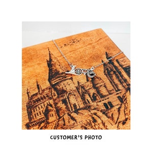 May include: A silver necklace with a charm that says "Love" with a Hogwarts castle design in the background.