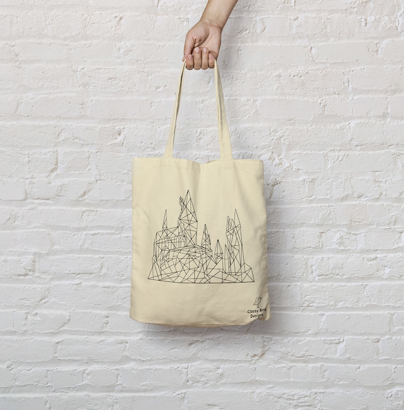 May include: A beige tote bag with a black geometric design of Hogwarts castle. The bag has a black handle and the text "Classy Bird Designs" in the bottom right corner.