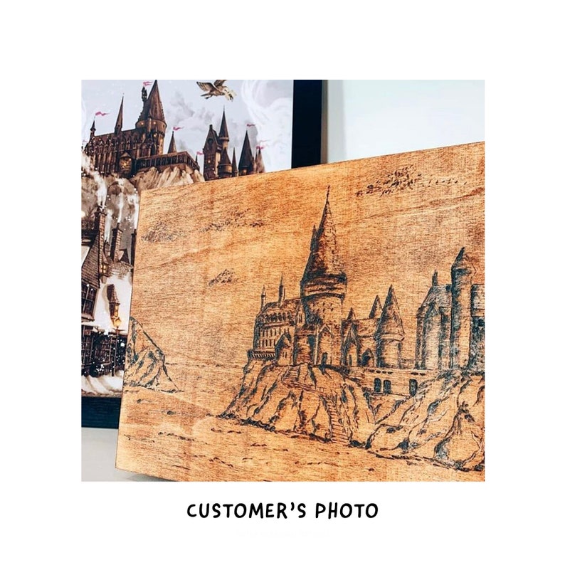 May include: A wood burned image of Hogwarts castle on a wooden plaque. The image is in black and white and shows the castle on a cliff overlooking a body of water.