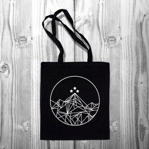 May include: Black canvas tote bag with a white geometric mountain design and five white stars in a circle.