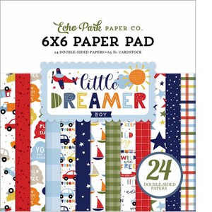 May include: A 6x6 paper pad with 24 double-sided papers featuring a blue, red, green, and yellow color scheme. The paper pad has a title that reads "Little Dreamer Boy" with a sun, airplane, and stars. The paper pad is from Echo Park Paper Co.