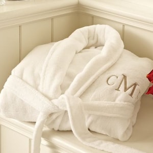 May include: White plush bathrobe with a white embroidered monogram "CM" on the front.