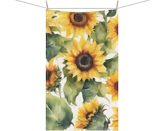 May include: A rectangular towel with a watercolor sunflower pattern. The design features large yellow sunflowers with brown centers and green leaves against a white background. The towel is hanging from a clothesline.