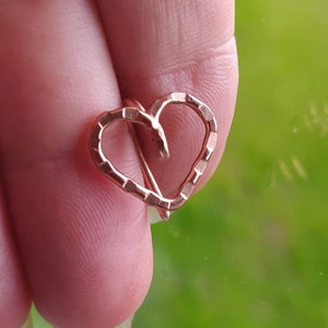 Puede incluir: Un colgante en forma de corazón de oro rosa con un acabado texturizado.