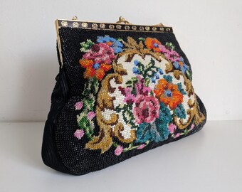 May include: Black beaded handbag with a colorful floral design. The bag features a gold-toned clasp and frame. The floral embroidery includes pink, orange, blue, and green accents, creating a vintage aesthetic.