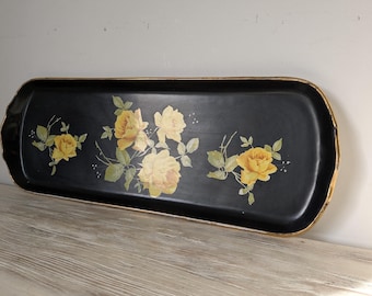 May include: A rectangular black serving tray with a gold trim and a floral design. The tray features yellow roses with green leaves and stems. The tray is made of a glossy material.