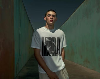 May include: A white crew neck t-shirt featuring a black and white graphic of a person in motion, with the word "MORA" printed in large black letters. The shirt is paired with light-colored pants.