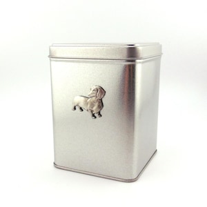 May include: Silver metal storage container with a dachshund silhouette embossed on the front.