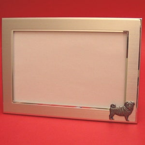 May include: Silver photo frame with a pewter pug figurine on the bottom right corner.
