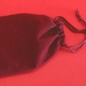 May include: A small, dark red velvet drawstring bag with a gathered top and a long cord.
