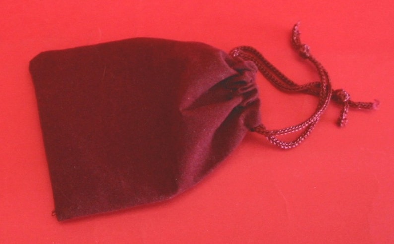 May include: A small, dark red velvet drawstring bag with a gathered top and a long cord.
